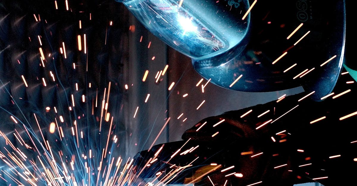 A focused welder works with metal in an industrial setting, creating vibrant sparks.